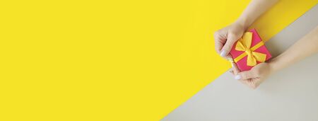 woman hand holds a gift box on a colored backgroundの写真素材