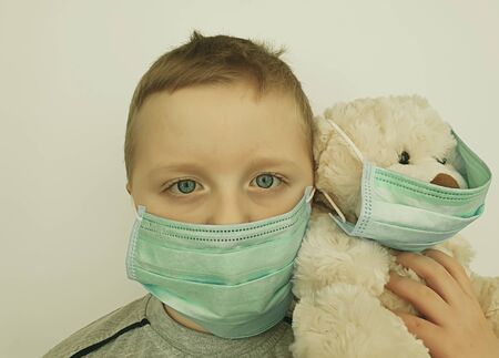 little boy with a toy bear in a protective mask