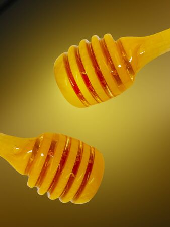 Honey wooden dipper, on yellow background tastyの写真素材