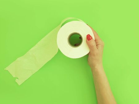 female hands hold toilet paper on a colored backgroundの写真素材