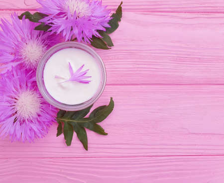 cream cosmetic flower on wooden background treatment
