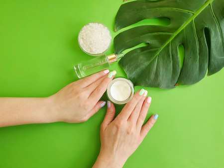 female hands beautiful manicure monstera leaf on a colored background creamの写真素材