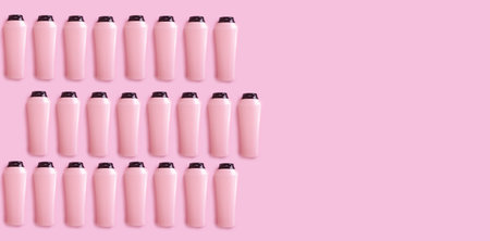 bottle of shampoo and balm on a colored pink background