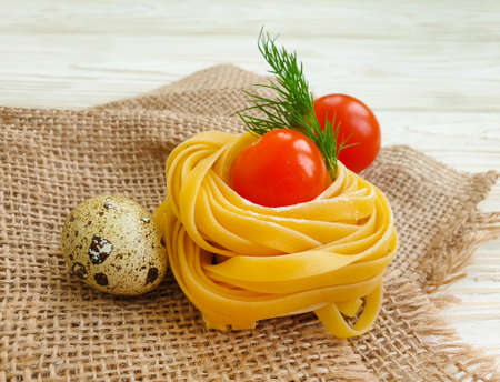 raw pasta, quail egg on a wooden backgroundの写真素材