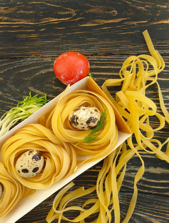 raw pasta, quail egg on a wooden backgroundの写真素材