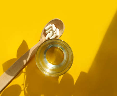 wooden spoon, collagen capsules on a colored backgroundの写真素材