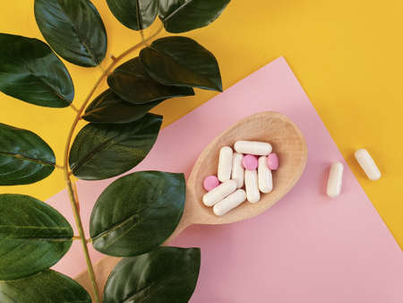 wooden spoon, collagen capsules on a colored background