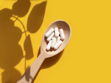 wooden spoon, collagen capsules on a colored backgroundの写真素材