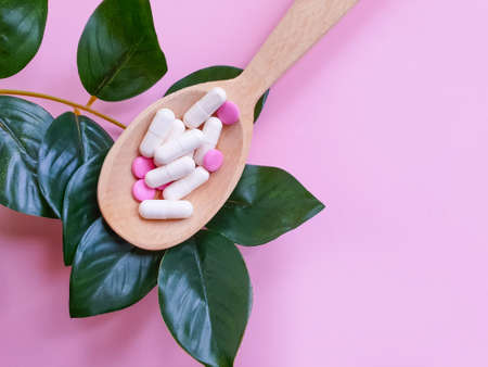 wooden spoon, collagen capsules on a colored background