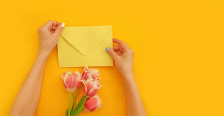 female hands hold an envelope, a bouquet of tulips