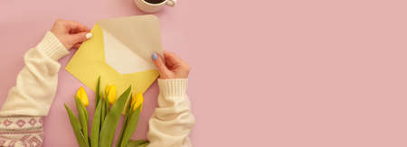 female hands hold an envelope, a bouquet of tulips