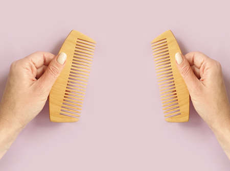 female hand holding a wooden comb on a colored backgroundの写真素材