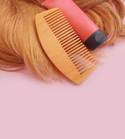 shampoo, wooden comb on a colored background