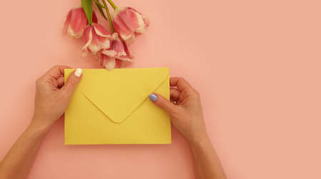 female hands hold an envelope, a bouquet of tulips