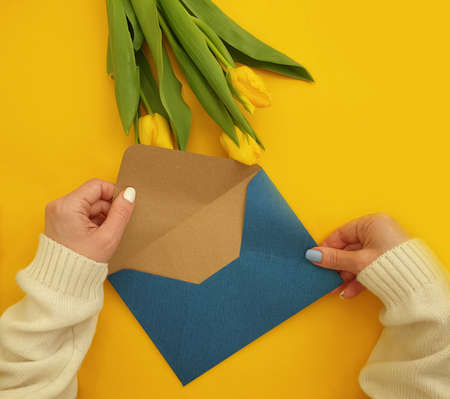 female hands hold an envelope, a bouquet of tulips