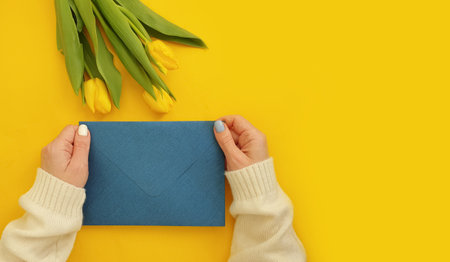 female hands hold an envelope, a bouquet of tulips