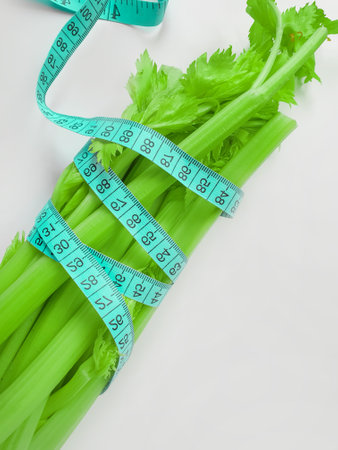 fresh celery measuring tape on white background