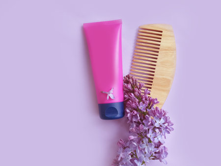 wooden comb, shampoo, lilac flower on a colored backgroundの写真素材