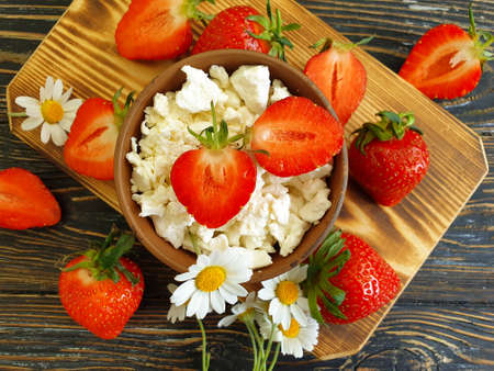 cottage cheese, strawberry, chamomile flower on a wooden backgroundの写真素材