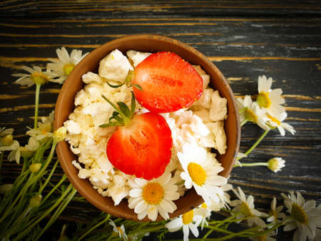 cottage cheese, strawberry, chamomile flower on a wooden backgroundの写真素材