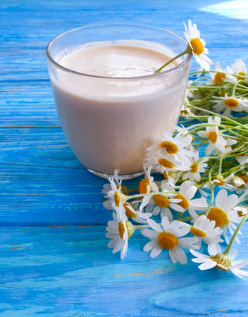 glass of milk, chamomile flower on wooden backgroundの写真素材
