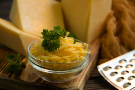 grated cheese, parsley on a wooden background