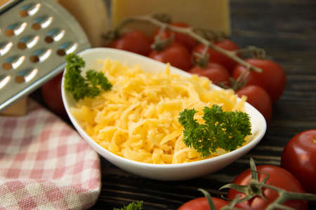 grated cheese, cherry tomatoes on a wooden background