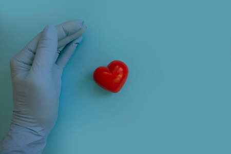 hand in a medical glove holds a heartの写真素材