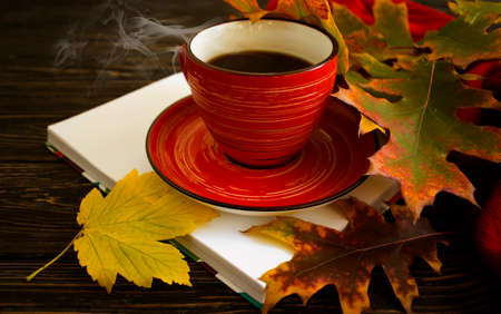 coffee cup, autumn leaves, book on wooden background