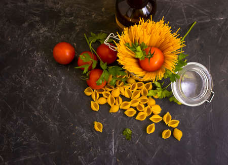dry pasta, tomato, oil on a concrete backgroundの写真素材