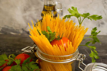 dry pasta, tomato, oil on a concrete backgroundの写真素材