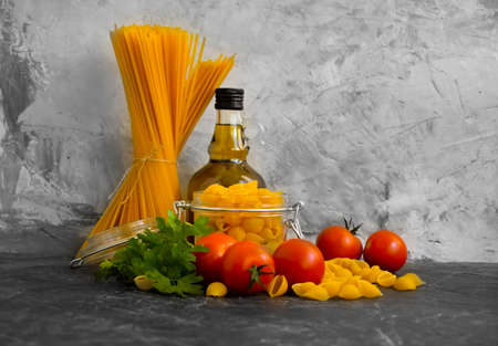 dry pasta, tomato, oil on a concrete backgroundの写真素材