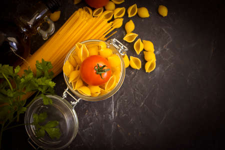 dry pasta, tomato, oil on a concrete backgroundの写真素材