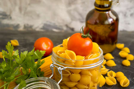 dry pasta, tomato, oil on a concrete backgroundの写真素材