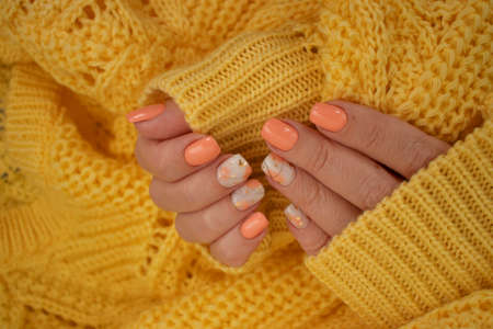 female hands beautiful manicure warm fabric sweater yellow