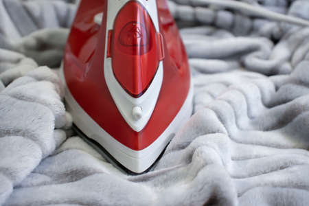 electric iron on a warm cloth backgroundの写真素材