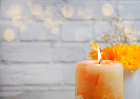 burning candle color chrysanthemum on a brick backgroundの写真素材