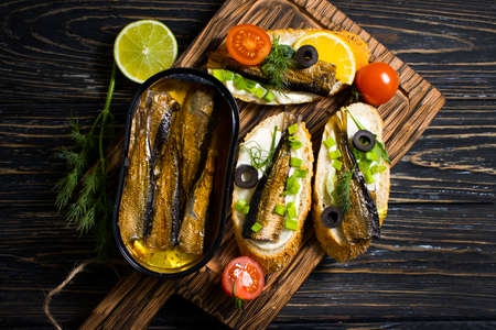 sprats in a can, fresh dill on wooden backgroundの写真素材