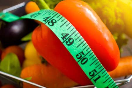 fresh vegetables, measuring tape on wooden background