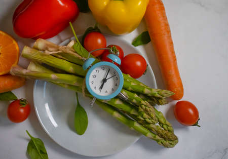 Fresh different vegetables, alarm clock backgroundの写真素材