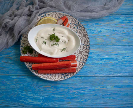 crab sticks, sauce in a plate on a wooden backgroundの写真素材
