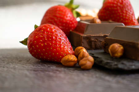 Dark chocolate, fresh strawberries, nuts on a dark backgroundの写真素材