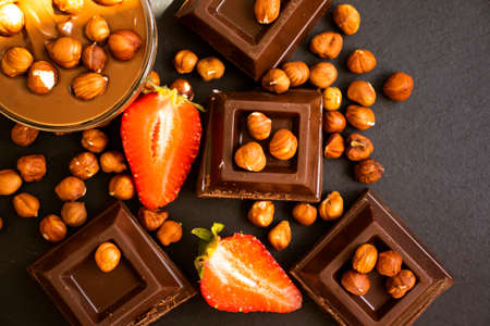 Dark chocolate, fresh strawberries, nuts on a dark backgroundの写真素材