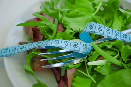 Lettuce leaves measuring tape on a plateの写真素材