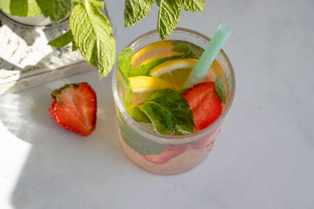 Lemonade with strawberries, mint, lemon on a light background