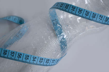 Bottle of water centimeter tape on a light background