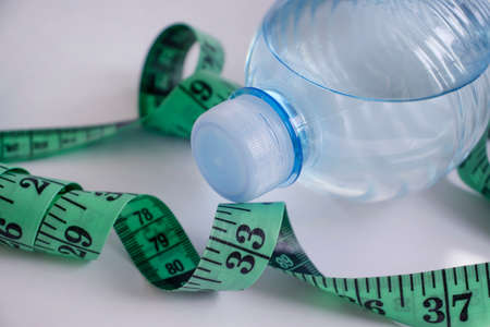 Bottle of water centimeter tape on a light background