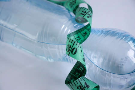 Bottle of water centimeter tape on a light backgroundの写真素材