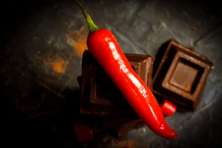 Black chocolate, red pepper on a dark background