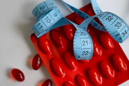 Pills, centimeter tape on a light backgroundの写真素材